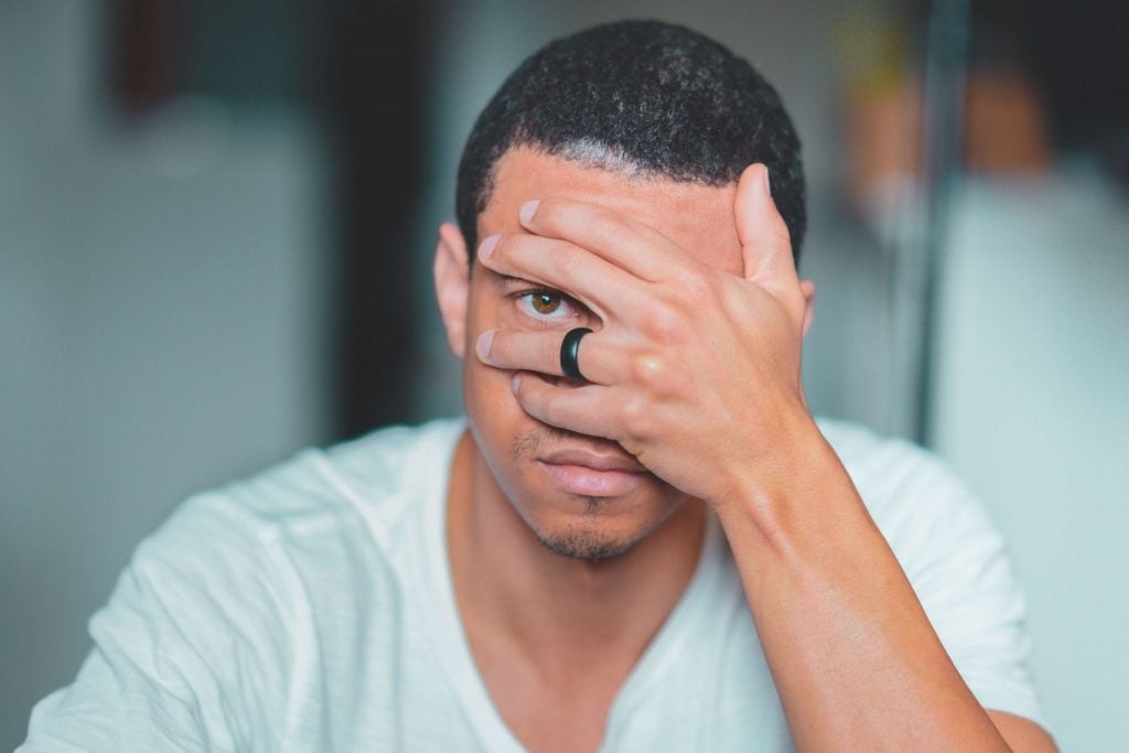 L'homme regarde à travers les doigts portant une bague noire
